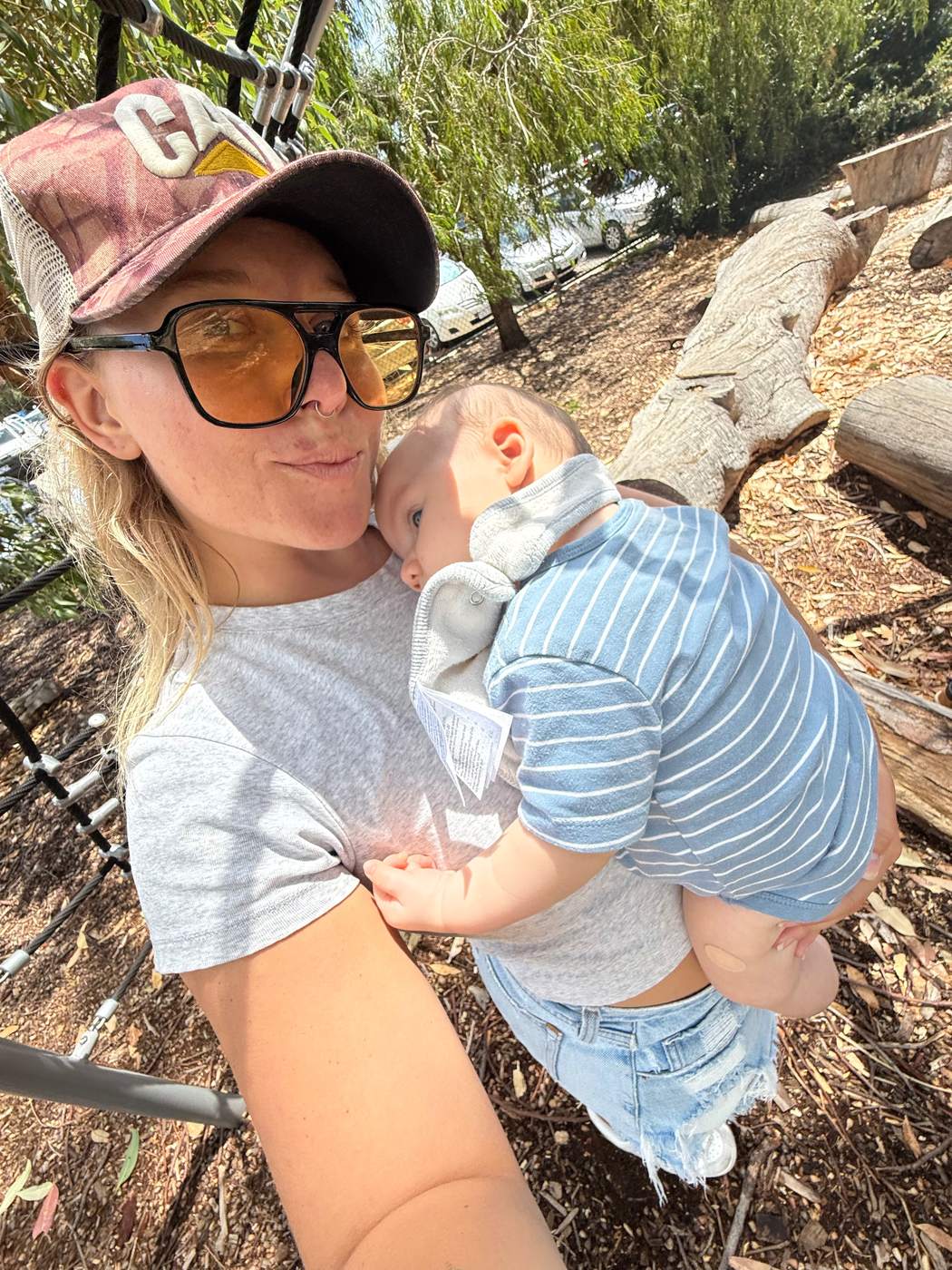 Ainsley holding a baby outdoors in dappled shade